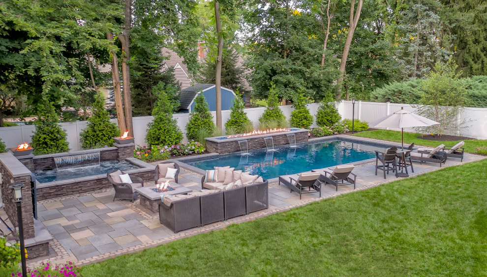 Large modern backyard rectangular pool in New York with brick pavers.