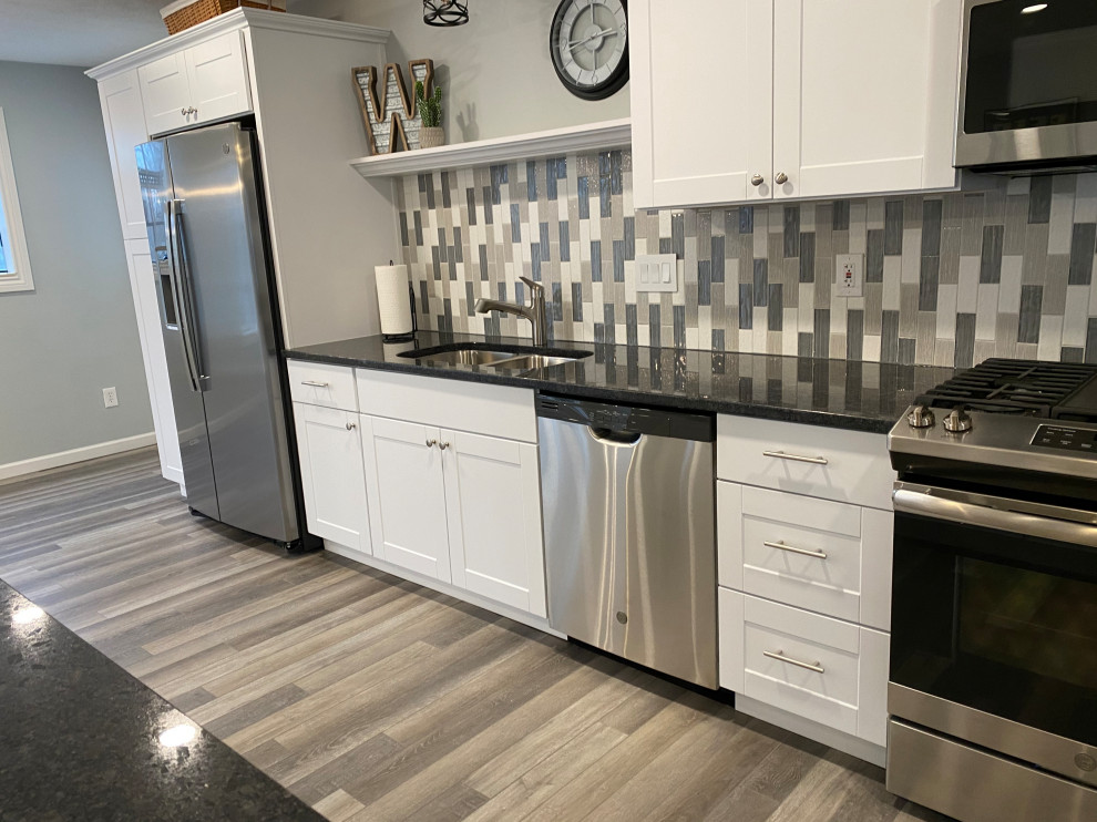 Large transitional l-shaped vinyl floor and gray floor open concept kitchen photo in Cincinnati with an undermount sink, raised-panel cabinets, white cabinets, granite countertops, multicolored backsplash, ceramic backsplash, stainless steel appliances, an island and black countertops