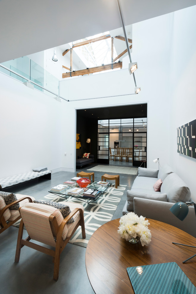 This is an example of an expansive contemporary formal open concept living room in London with white walls and concrete floors.