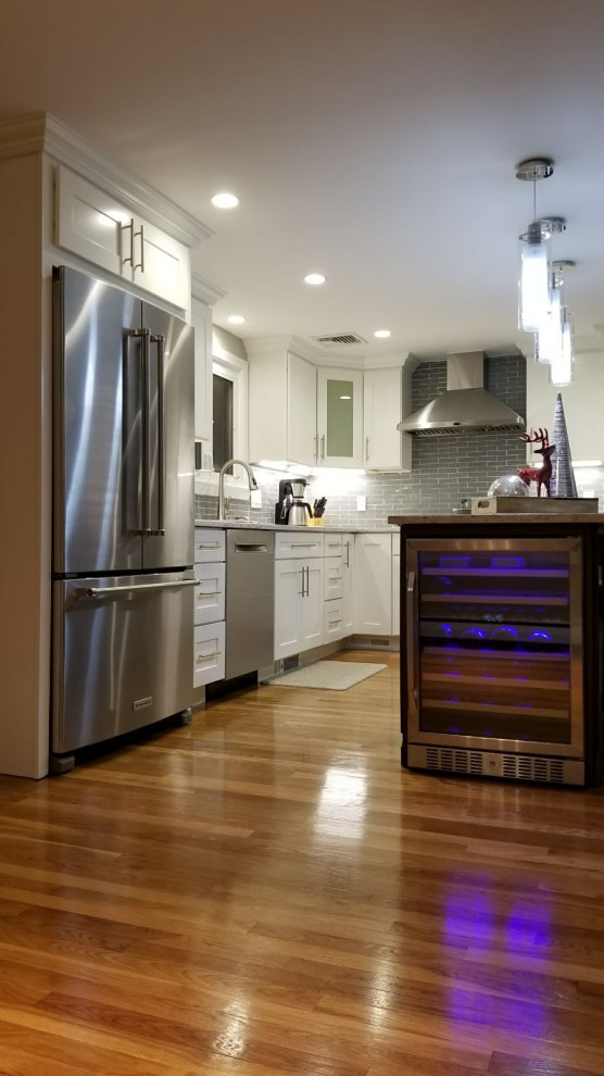Inspiration for a mid-sized transitional l-shaped dark wood floor and brown floor open concept kitchen remodel with an undermount sink, shaker cabinets, white cabinets, gray backsplash, stainless steel appliances, an island and white countertops