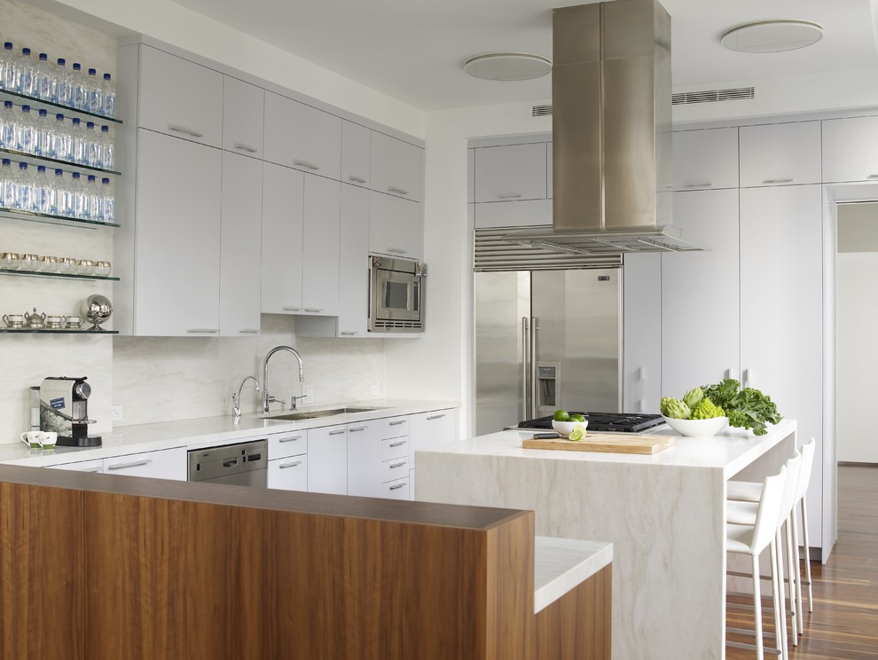 Mid-sized contemporary u-shaped kitchen in New York with an undermount sink, flat-panel cabinets, grey cabinets, concrete benchtops, white splashback, stainless steel appliances, medium hardwood floors and with island.