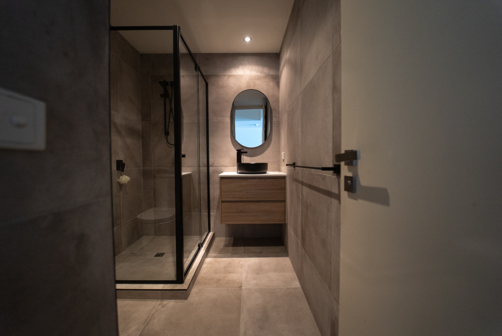 Design ideas for a mid-sized modern kids bathroom in Melbourne with furniture-like cabinets, light wood cabinets, a one-piece toilet, gray tile, porcelain tile, grey walls, porcelain floors, engineered quartz benchtops, grey floor, white benchtops, a single vanity and a floating vanity.