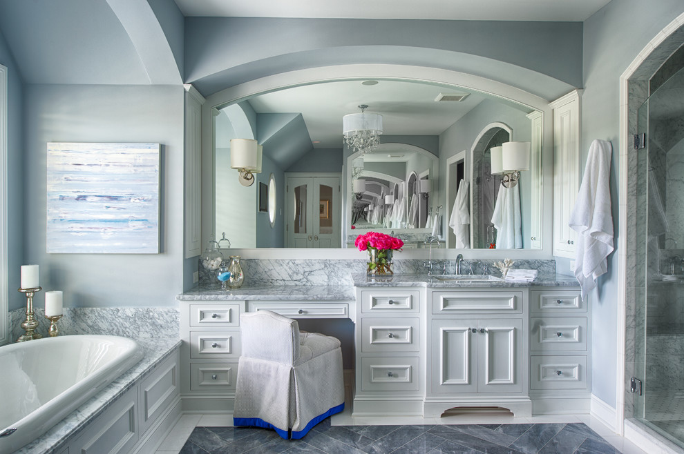 Inspiration for a mid-sized transitional master bathroom in Minneapolis with recessed-panel cabinets, white cabinets, a drop-in tub, an alcove shower, gray tile, porcelain tile, grey walls, porcelain floors, an undermount sink, marble benchtops, grey floor and a hinged shower door.