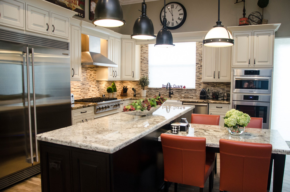 Example of a large transitional l-shaped porcelain tile open concept kitchen design in Miami with a farmhouse sink, raised-panel cabinets, white cabinets, granite countertops, multicolored backsplash, mosaic tile backsplash, stainless steel appliances and an island