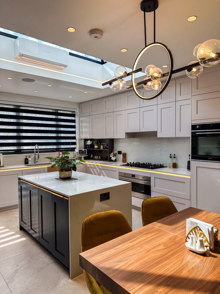 Inspiration for a large traditional l-shaped kitchen/diner in London with a built-in sink, shaker cabinets, blue cabinets, quartz worktops, white splashback, engineered quartz splashback, integrated appliances, porcelain flooring, an island, beige floors, white worktops and feature lighting.