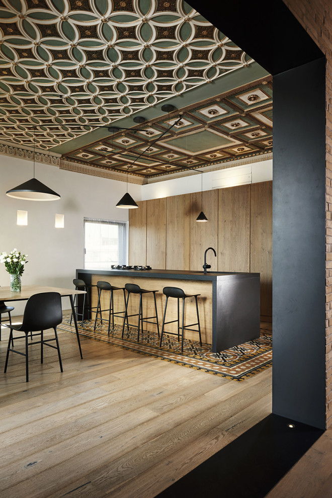 Moderne Küche mit hellem Holzboden, Kücheninsel, schwarzer Arbeitsplatte und Kassettendecke in Rom