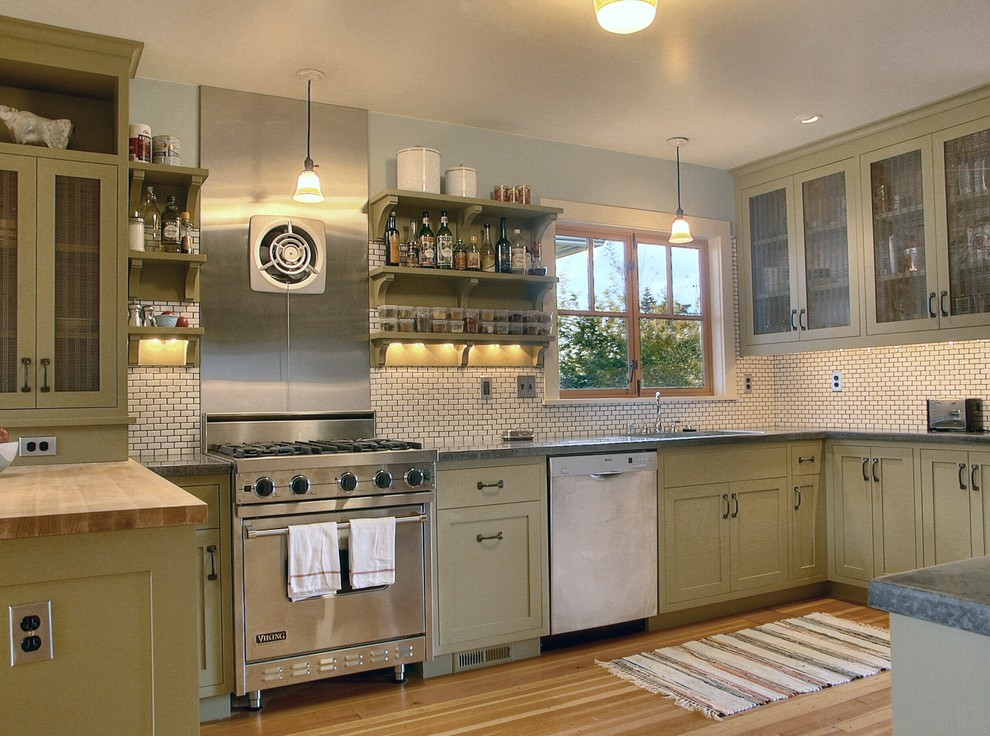 Photo of a mid-sized arts and crafts separate kitchen in Seattle with an undermount sink, shaker cabinets, green cabinets, solid surface benchtops, beige splashback, subway tile splashback, stainless steel appliances, medium hardwood floors and a peninsula.