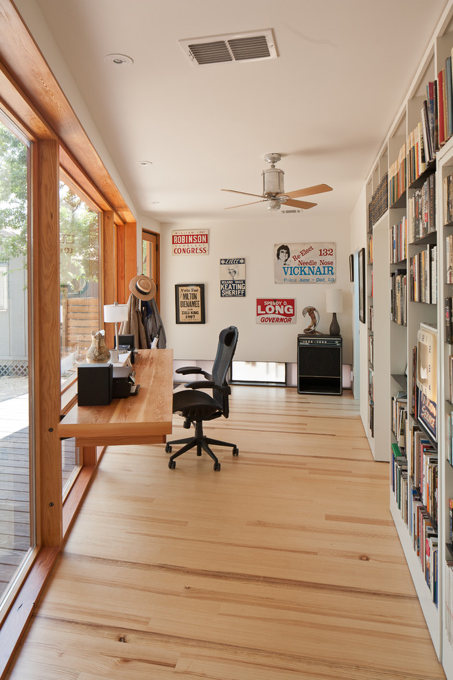 Contemporary home office in Austin with white walls, medium hardwood floors and a built-in desk.