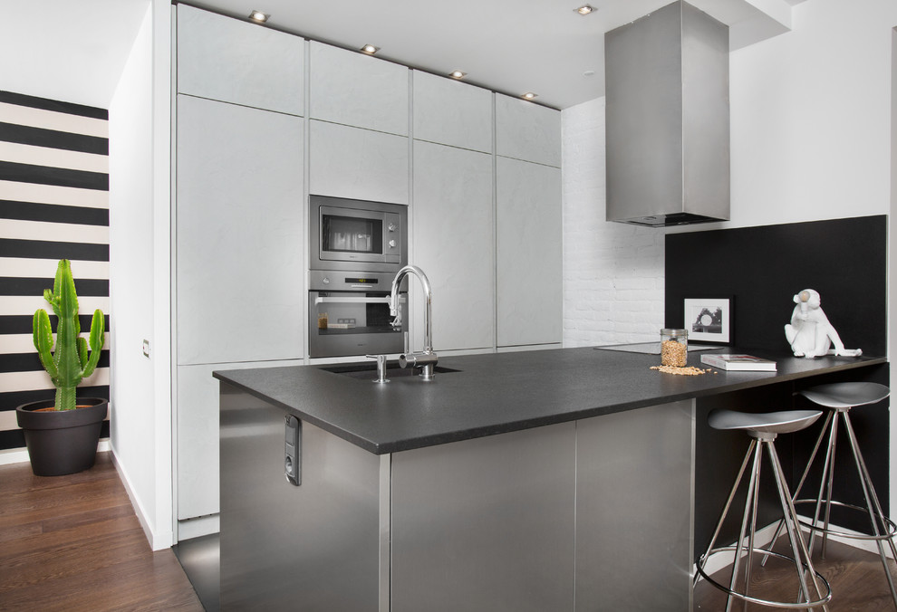 Inspiration for a contemporary galley kitchen in Barcelona with an undermount sink, flat-panel cabinets, grey cabinets, stainless steel appliances, dark hardwood floors and a peninsula.
