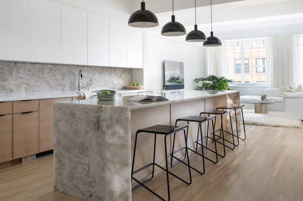 Design ideas for a large contemporary single-wall kitchen/diner in New York with a submerged sink, flat-panel cabinets, white cabinets, quartz worktops, grey splashback, stone slab splashback, stainless steel appliances, light hardwood flooring, an island and grey worktops.