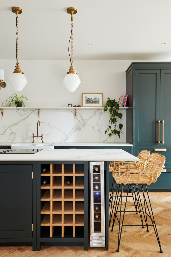 Inspiration for a large traditional single-wall eat-in kitchen in London with a farmhouse sink, shaker cabinets, green cabinets, solid surface benchtops, grey splashback, engineered quartz splashback, stainless steel appliances, dark hardwood floors, with island, brown floor and grey benchtop.