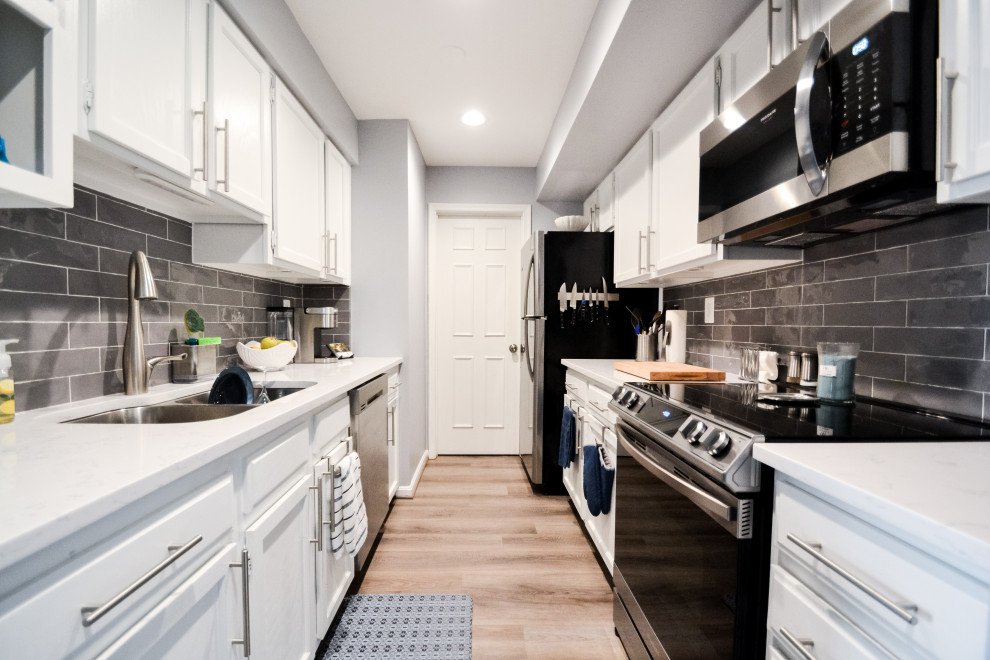 Small contemporary galley kitchen in DC Metro with a submerged sink, shaker cabinets, white cabinets, engineered stone countertops, grey splashback, ceramic splashback, stainless steel appliances, no island and white worktops.