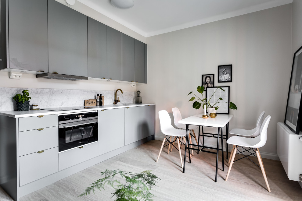 Photo of a scandinavian kitchen in Stockholm with a drop-in sink, marble benchtops and light hardwood floors.