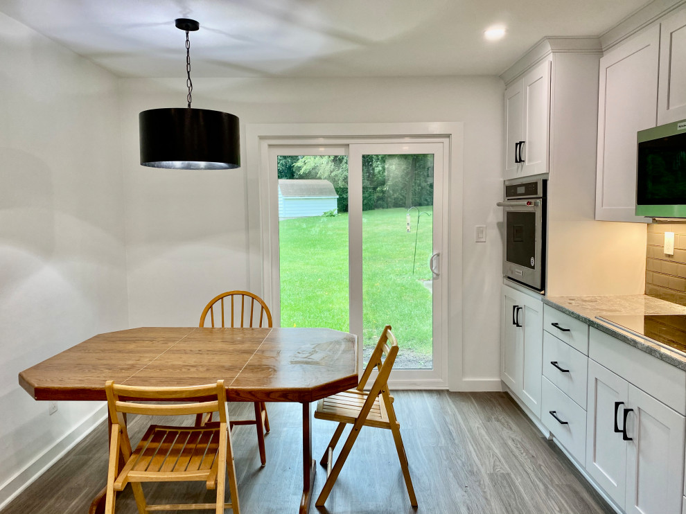 Example of a small transitional u-shaped vinyl floor and gray floor eat-in kitchen design in Milwaukee with a double-bowl sink, shaker cabinets, white cabinets, granite countertops, gray backsplash, glass tile backsplash, stainless steel appliances, a peninsula and gray countertops