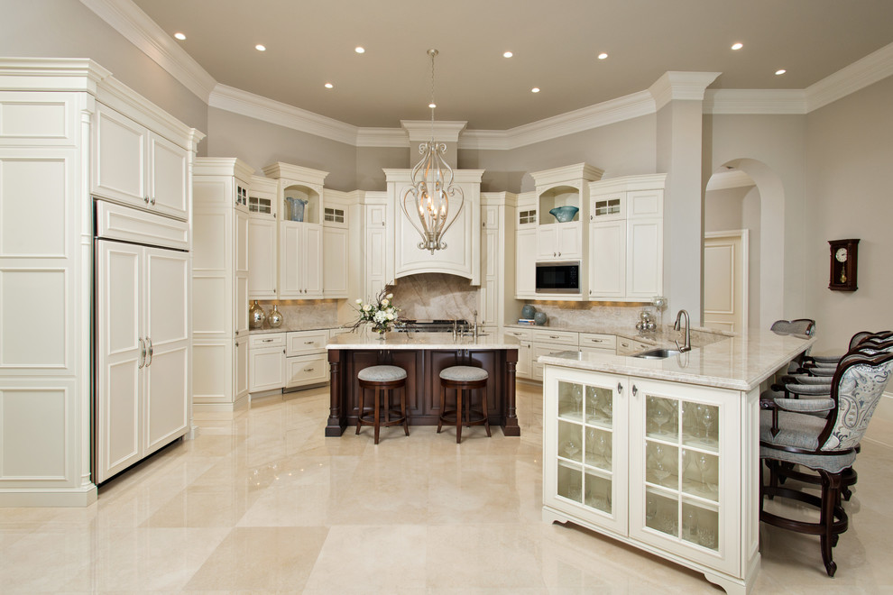Traditional u-shaped kitchen in Other with quartzite benchtops, travertine floors, a double-bowl sink, recessed-panel cabinets, white cabinets, beige splashback, panelled appliances, with island, beige floor and beige benchtop.