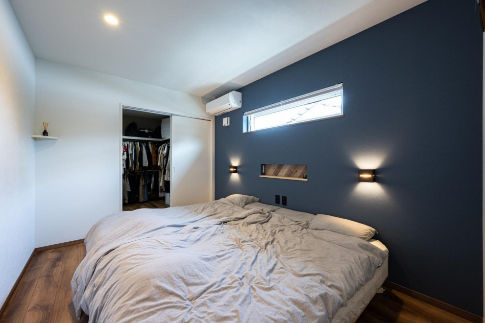 Cette photo montre une chambre parentale scandinave avec un mur bleu, parquet foncé, un sol marron, un plafond en papier peint et du papier peint.