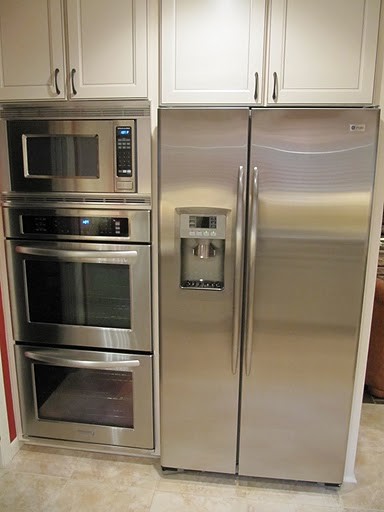 Inspiration for a large transitional l-shaped porcelain tile and beige floor eat-in kitchen remodel in Houston with a double-bowl sink, shaker cabinets, white cabinets, granite countertops, beige backsplash, travertine backsplash and a peninsula