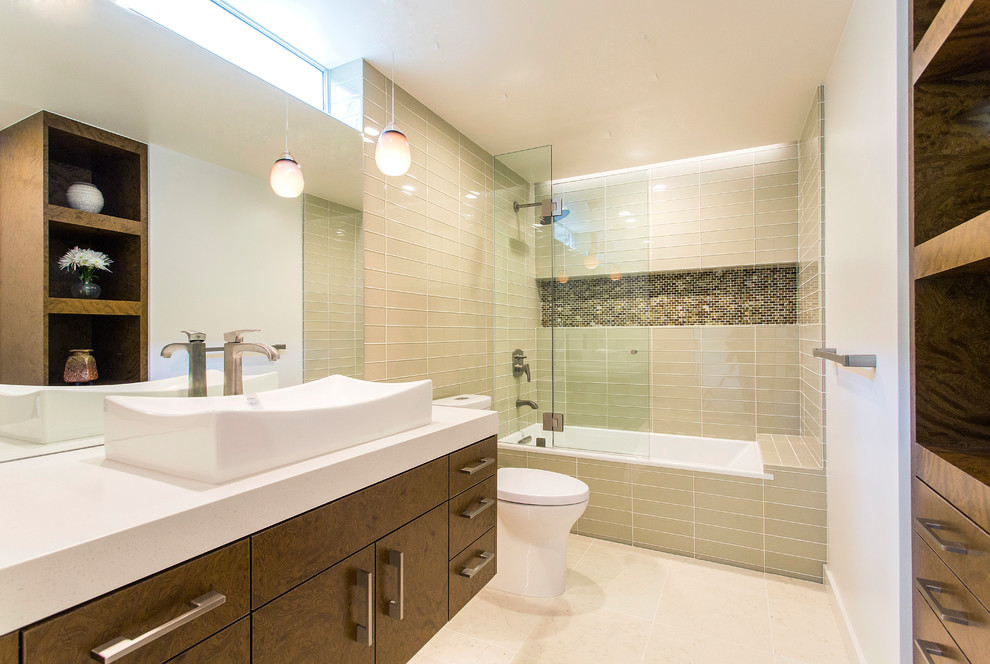 Example of a mid-sized trendy master beige tile and glass tile limestone floor and beige floor drop-in bathtub design in San Diego with flat-panel cabinets, medium tone wood cabinets, white walls, a vessel sink, quartz countertops and a hinged shower door