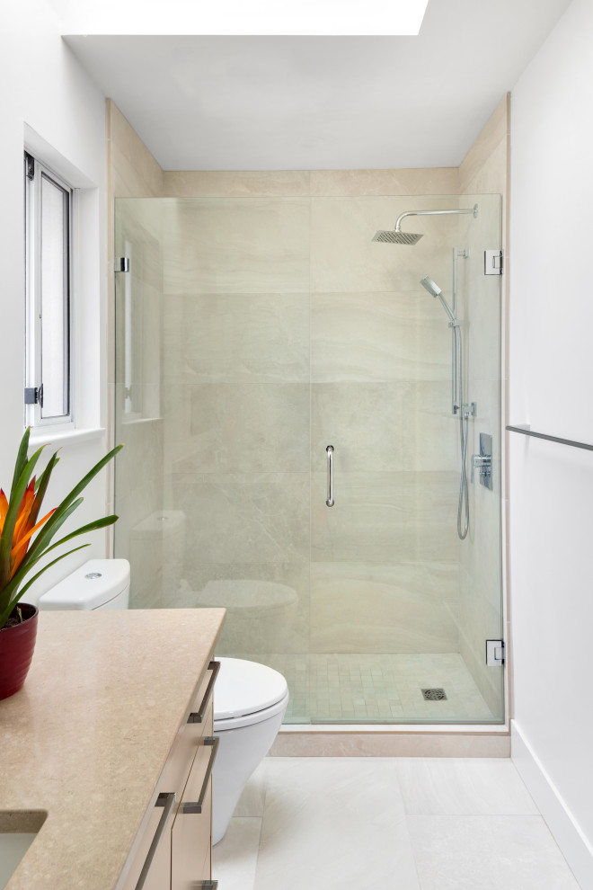 This is an example of a contemporary ensuite bathroom in Vancouver with flat-panel cabinets, light wood cabinets, an alcove shower, a one-piece toilet, white tiles, porcelain tiles, white walls, porcelain flooring, a built-in sink, white floors, brown worktops, a single sink, a freestanding vanity unit, a vaulted ceiling, granite worktops and a hinged door.
