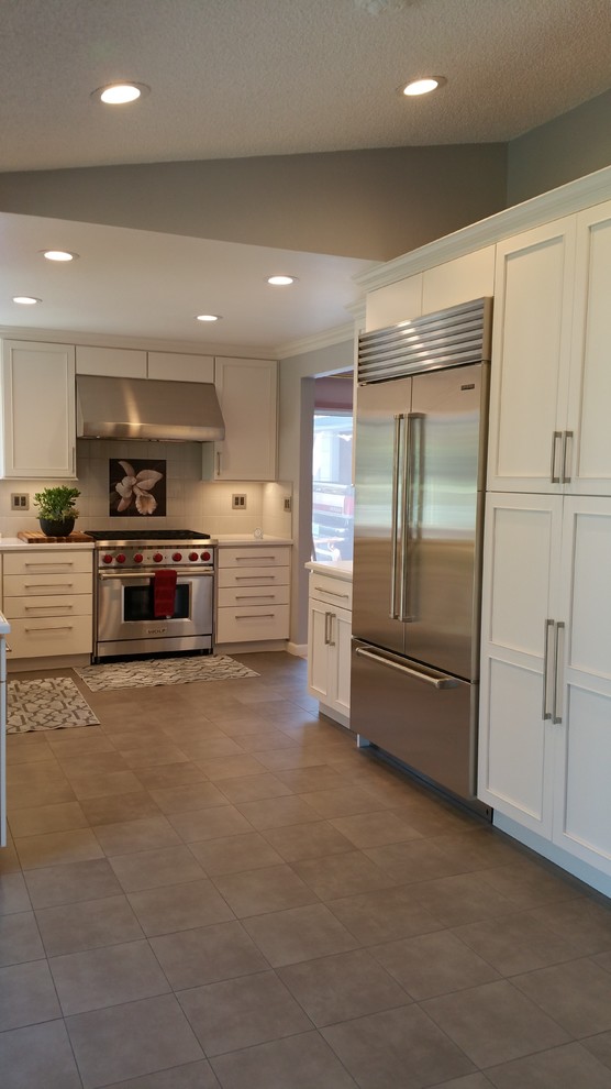 This is an example of a large transitional u-shaped open plan kitchen in San Francisco with stainless steel appliances, beaded inset cabinets, white cabinets, quartzite benchtops, white splashback, subway tile splashback, ceramic floors and with island.