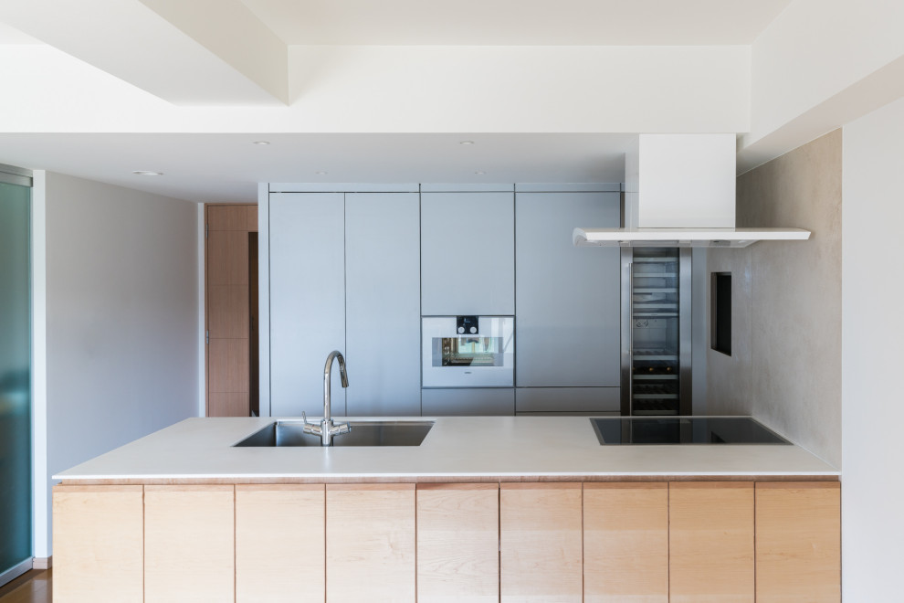 This is an example of a mid-sized modern galley separate kitchen in Other with flat-panel cabinets, grey cabinets, solid surface benchtops, a peninsula, white benchtop, an undermount sink, beige splashback, timber splashback, stainless steel appliances, plywood floors, beige floor and wallpaper.