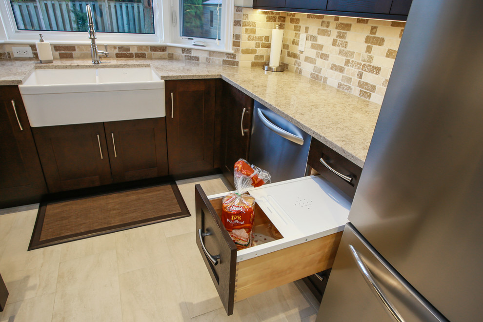 Example of a mid-sized transitional u-shaped porcelain tile enclosed kitchen design in Toronto with a farmhouse sink, shaker cabinets, dark wood cabinets, quartz countertops, beige backsplash, stone tile backsplash, stainless steel appliances and no island