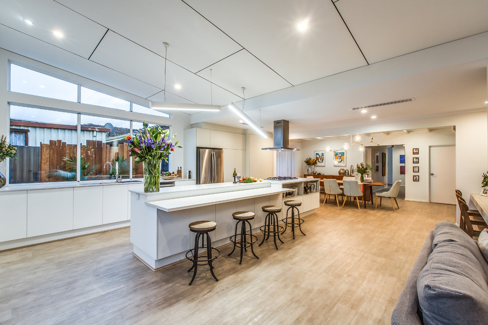 Large contemporary galley open plan kitchen in Perth with white cabinets, quartz benchtops, with island, an undermount sink, flat-panel cabinets, window splashback, stainless steel appliances, light hardwood floors and beige floor.