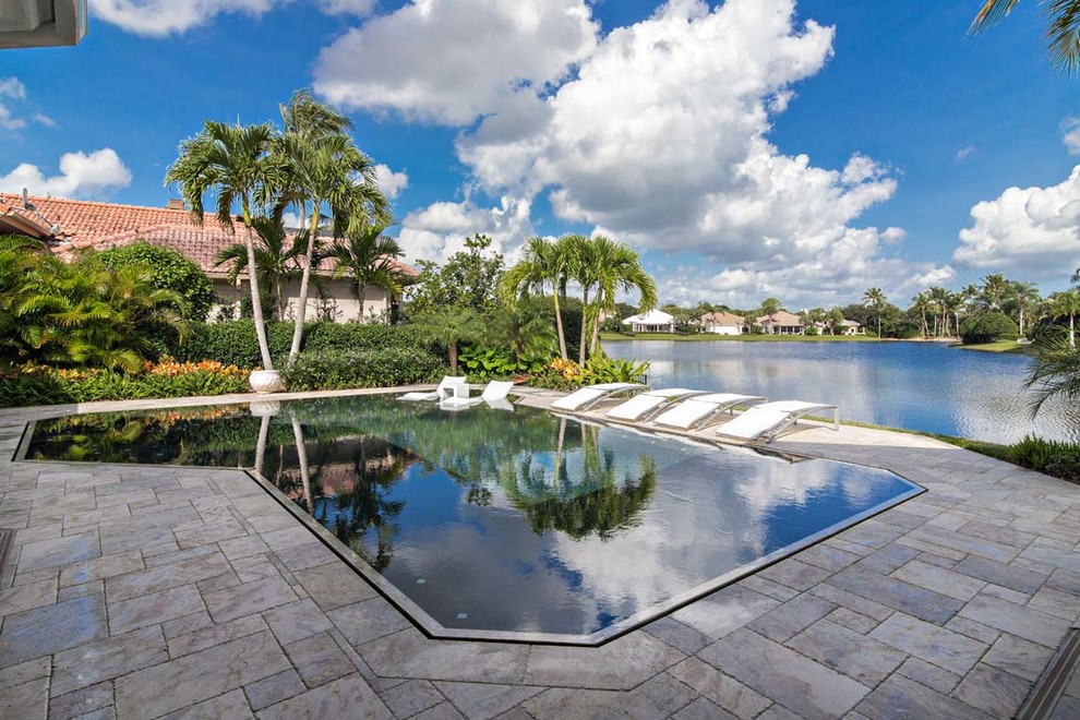 Inspiration for a mid-sized contemporary backyard custom-shaped lap pool in Miami with a hot tub and concrete pavers.