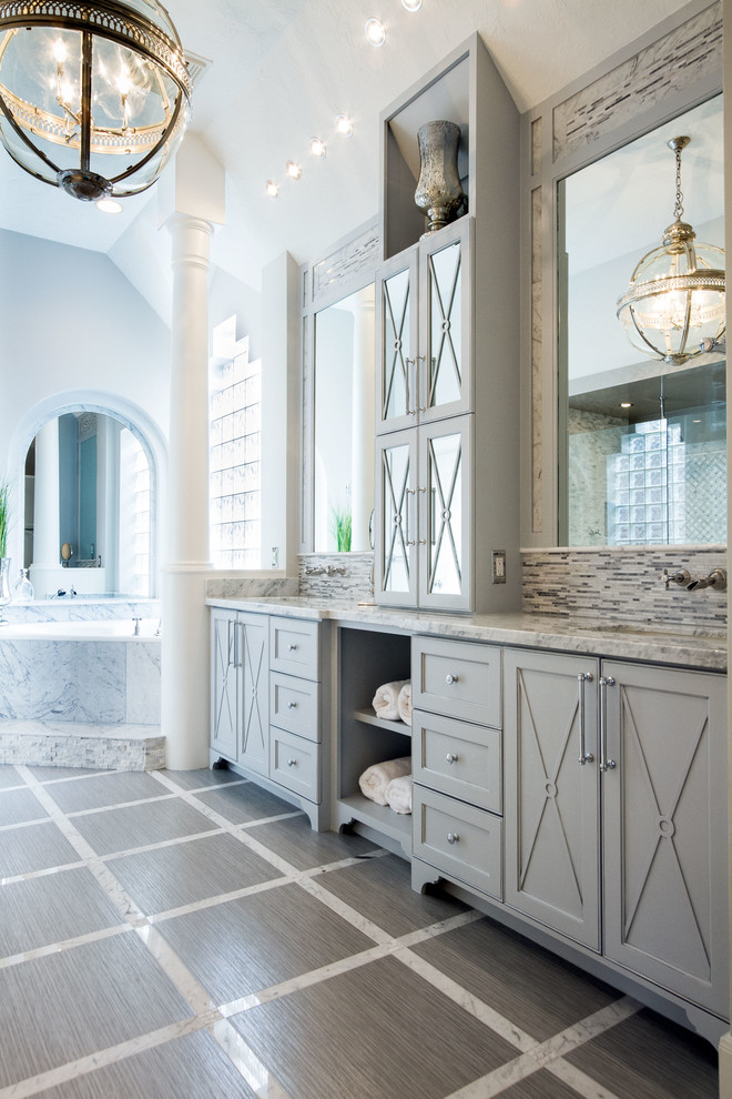 This is an example of a large contemporary master bathroom in Houston with an undermount sink, furniture-like cabinets, grey cabinets, marble benchtops, a corner tub, a curbless shower, a one-piece toilet, multi-coloured tile and porcelain tile.