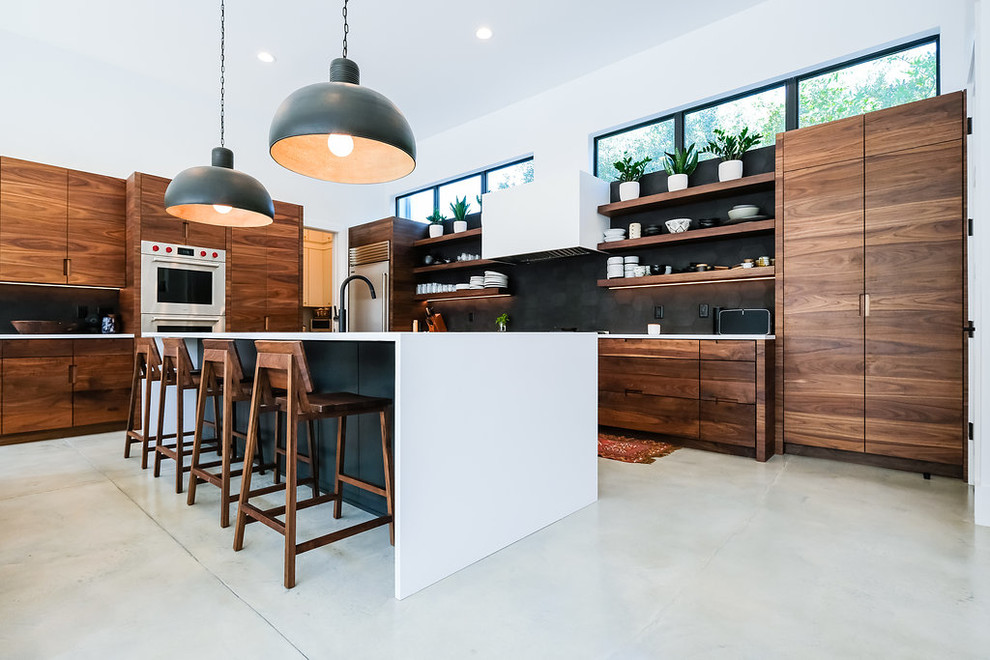 Inspiration for a large contemporary l-shaped open plan kitchen in Other with an undermount sink, flat-panel cabinets, medium wood cabinets, quartz benchtops, black splashback, cement tile splashback, stainless steel appliances, concrete floors, with island and grey floor.