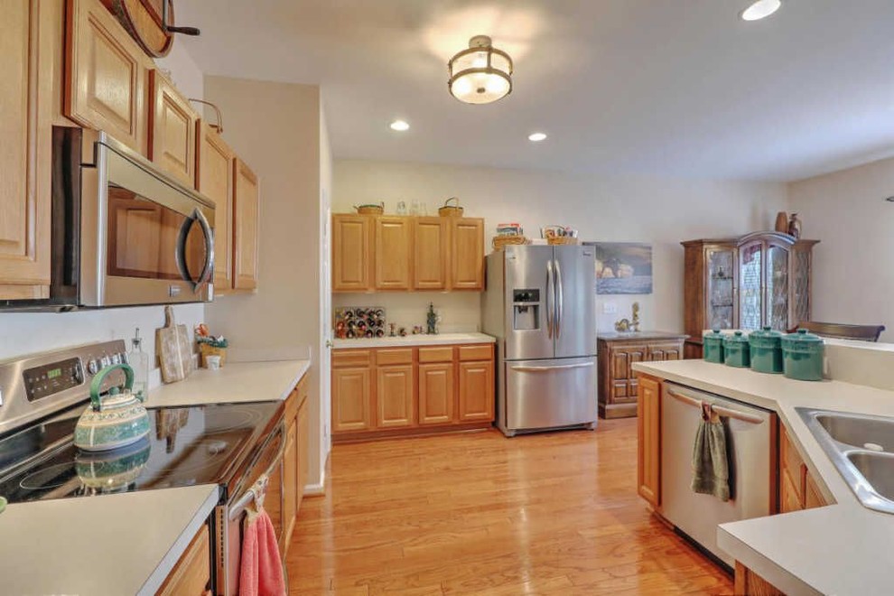 Kitchen - mid-sized u-shaped medium tone wood floor and brown floor kitchen idea in Charleston with an undermount sink, raised-panel cabinets, beige cabinets, granite countertops, brown backsplash, ceramic backsplash, stainless steel appliances and beige countertops