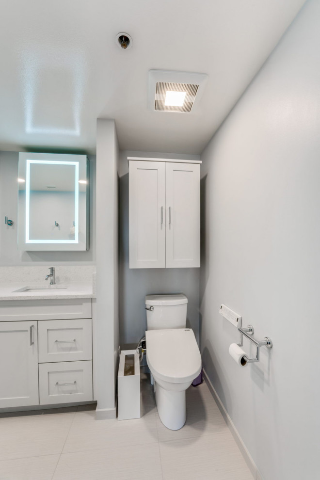 Пример оригинального дизайна: маленькая главная ванная комната в современном стиле с фасадами с утопленной филенкой, белыми фасадами, двойным душем, биде, белой плиткой, белыми стенами, полом из керамогранита, врезной раковиной, столешницей из искусственного кварца, белым полом, душем с распашными дверями, белой столешницей, сиденьем для душа, тумбой под две раковины, встроенной тумбой и панелями на части стены для на участке и в саду