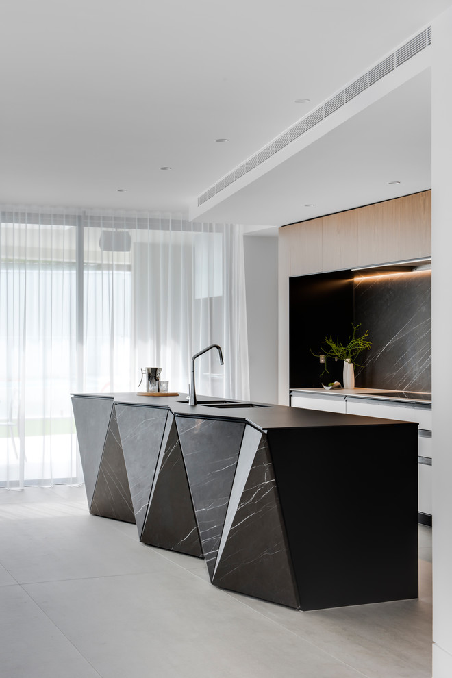 Large contemporary galley kitchen pantry in Sydney with a double-bowl sink, flat-panel cabinets, white cabinets, recycled glass benchtops, grey splashback, marble splashback, black appliances, porcelain floors, with island, grey floor and black benchtop.