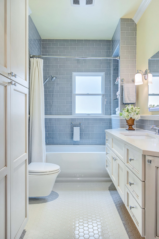 Design ideas for a small transitional bathroom in Dallas with an undermount sink, recessed-panel cabinets, white cabinets, engineered quartz benchtops, an alcove tub, a shower/bathtub combo, a wall-mount toilet, gray tile, ceramic tile, white walls and ceramic floors.