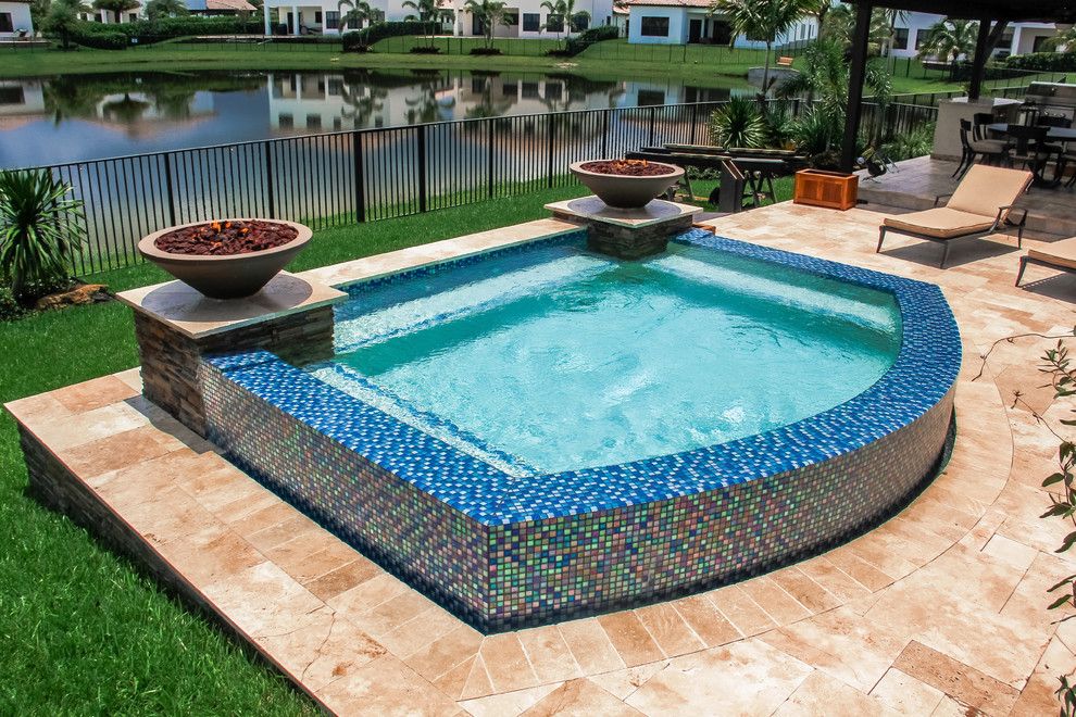 Design ideas for a small modern backyard custom-shaped aboveground pool in Miami with a hot tub and natural stone pavers.