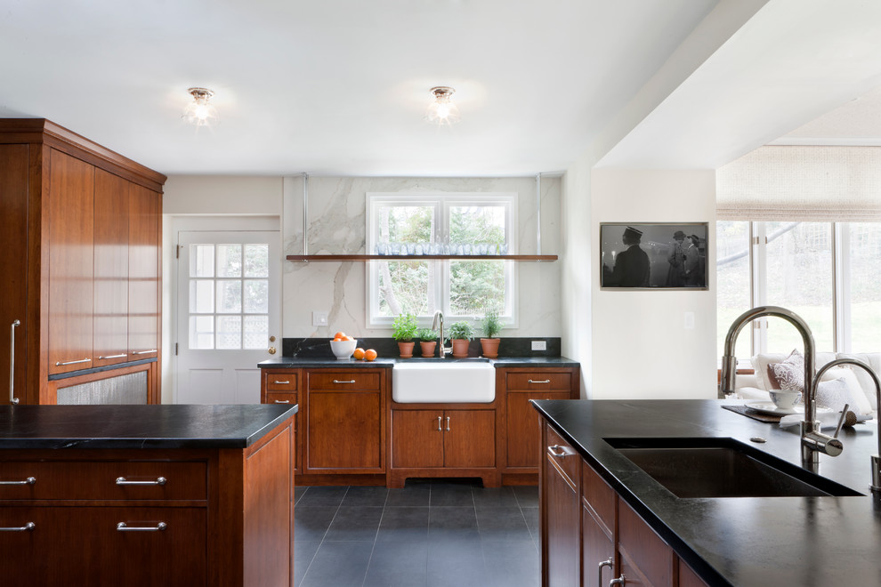 Mid-sized transitional kitchen in DC Metro with a peninsula, flat-panel cabinets, medium wood cabinets, soapstone benchtops, white splashback, porcelain splashback, stainless steel appliances, a farmhouse sink and porcelain floors.