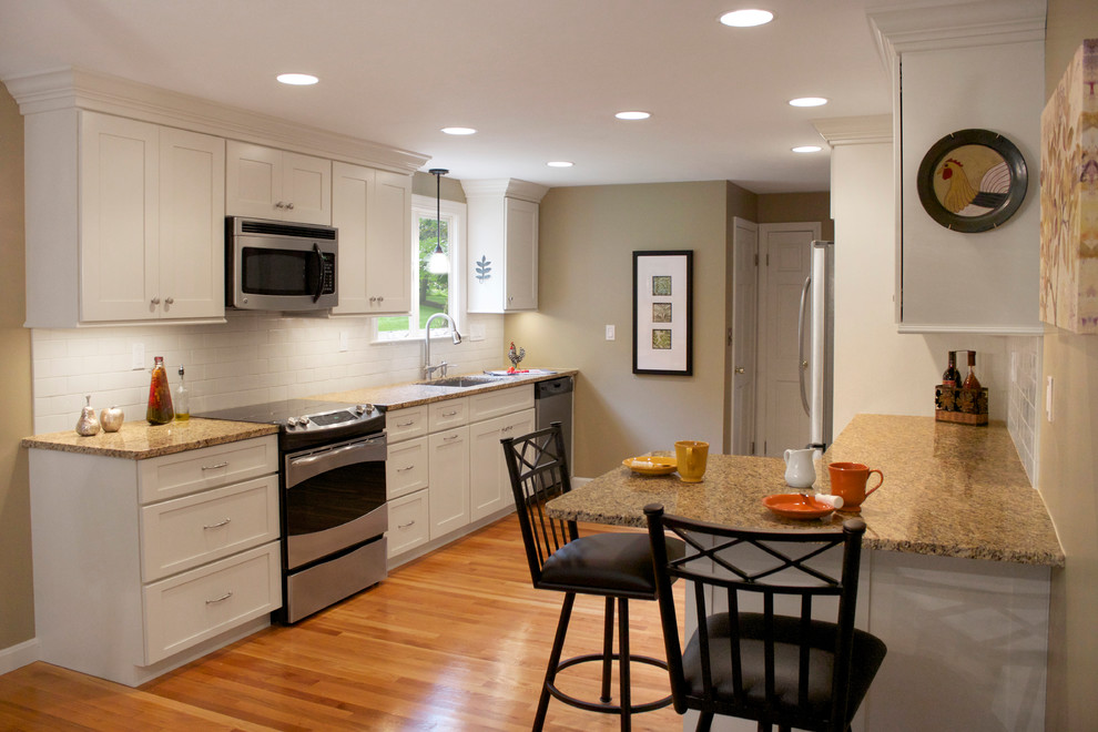 Design ideas for a mid-sized transitional galley eat-in kitchen in Boston with an undermount sink, shaker cabinets, white cabinets, granite benchtops, white splashback, subway tile splashback, stainless steel appliances, medium hardwood floors and a peninsula.