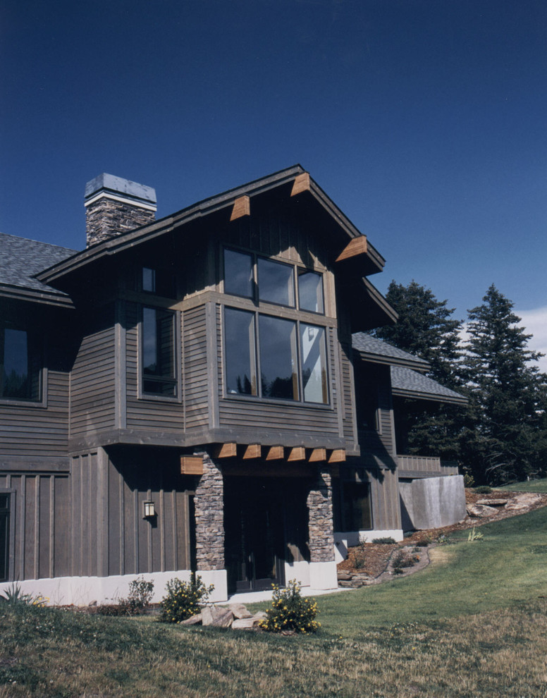 Photo of a mid-sized country two-storey grey exterior in Other with wood siding and a shed roof.