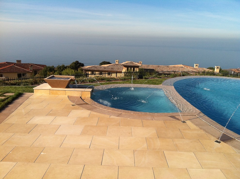 Large mediterranean backyard custom-shaped infinity pool in Orange County with tile and a hot tub.