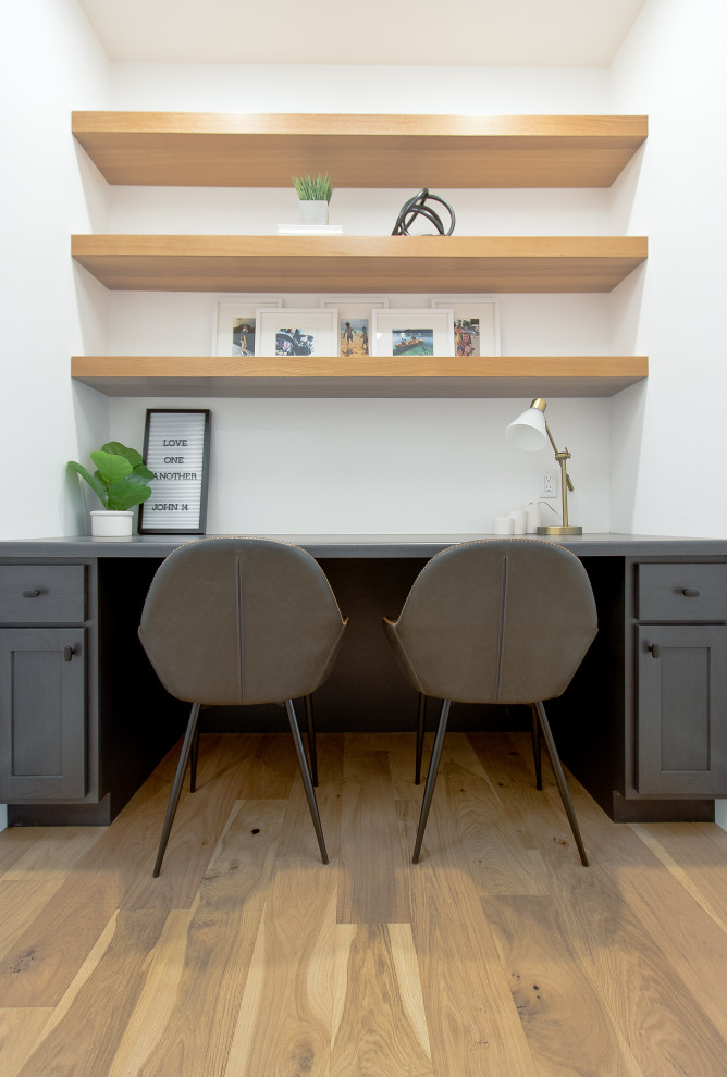 Imagen de despacho clásico renovado con paredes blancas, suelo de madera clara, escritorio empotrado y suelo marrón
