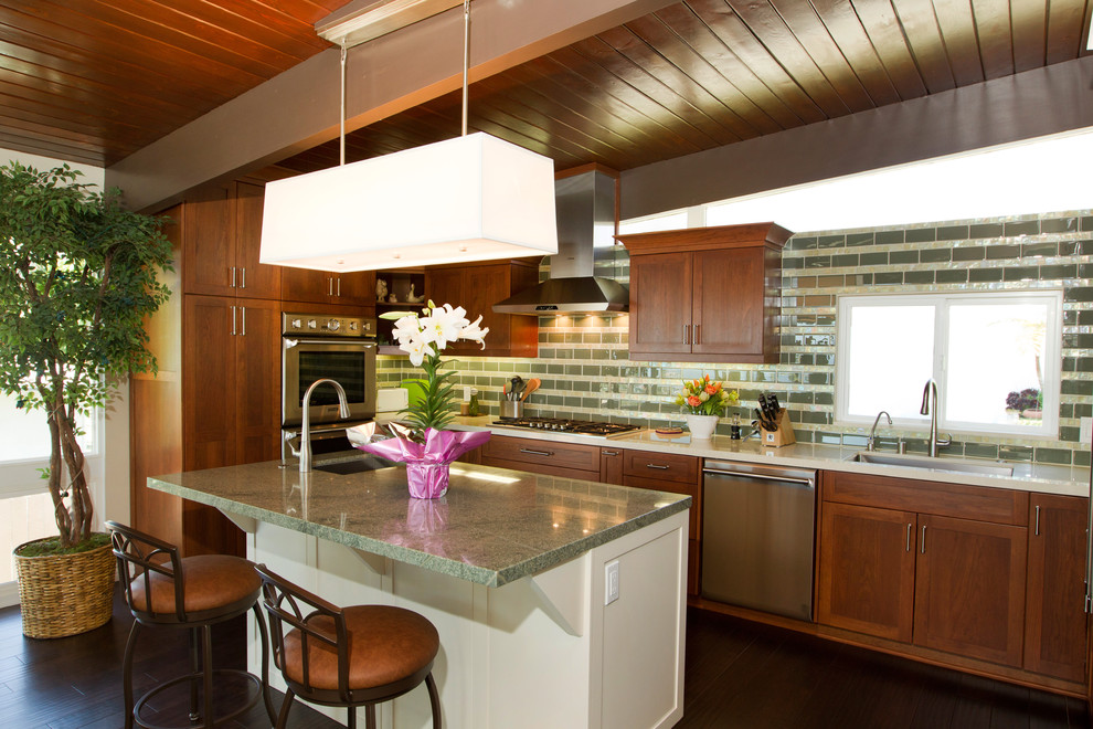 This is an example of a large contemporary u-shaped open plan kitchen in Los Angeles with an undermount sink, shaker cabinets, dark wood cabinets, quartz benchtops, green splashback, subway tile splashback, stainless steel appliances, dark hardwood floors, with island and brown floor.