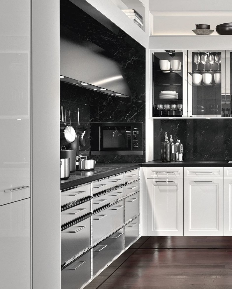 Inspiration for a large traditional l-shaped eat-in kitchen in Seattle with a drop-in sink, recessed-panel cabinets, white cabinets, granite benchtops, black splashback, marble splashback, panelled appliances, light hardwood floors, no island, brown floor and black benchtop.