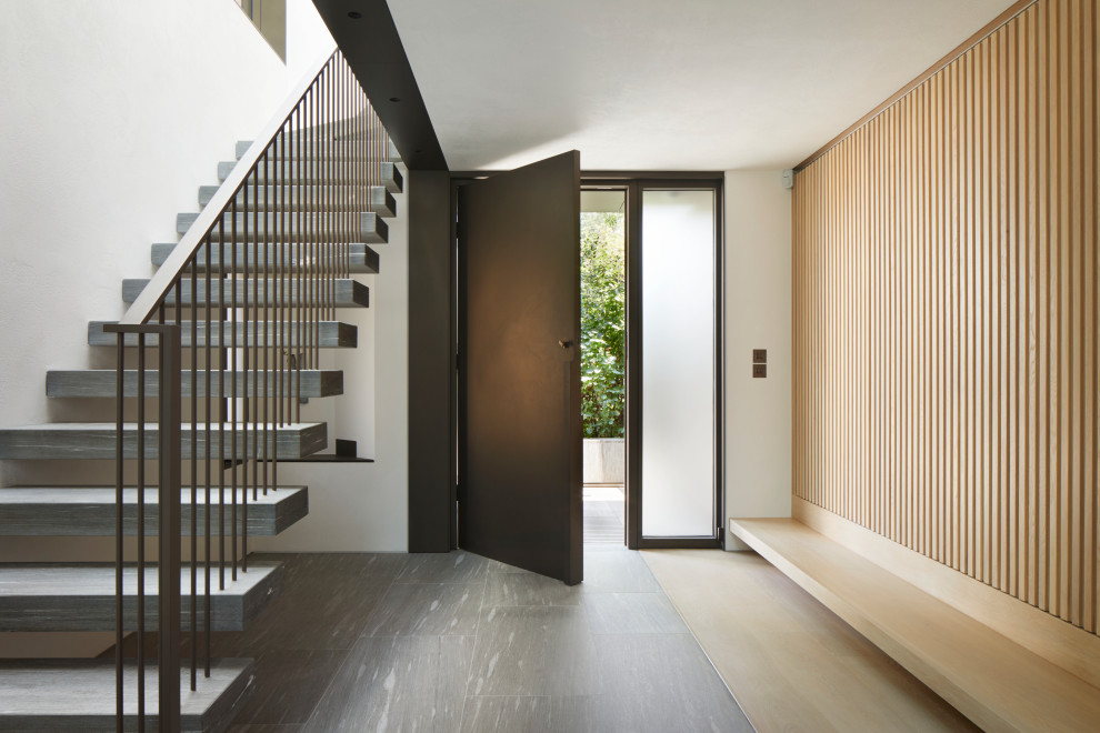 This is an example of a mid-sized contemporary foyer in London with white walls, light hardwood floors, a single front door, a metal front door and beige floor.