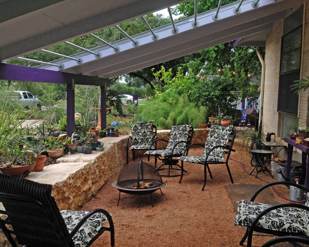 This is an example of a mid-sized tropical backyard partial sun formal garden for summer in Austin with a retaining wall and mulch.