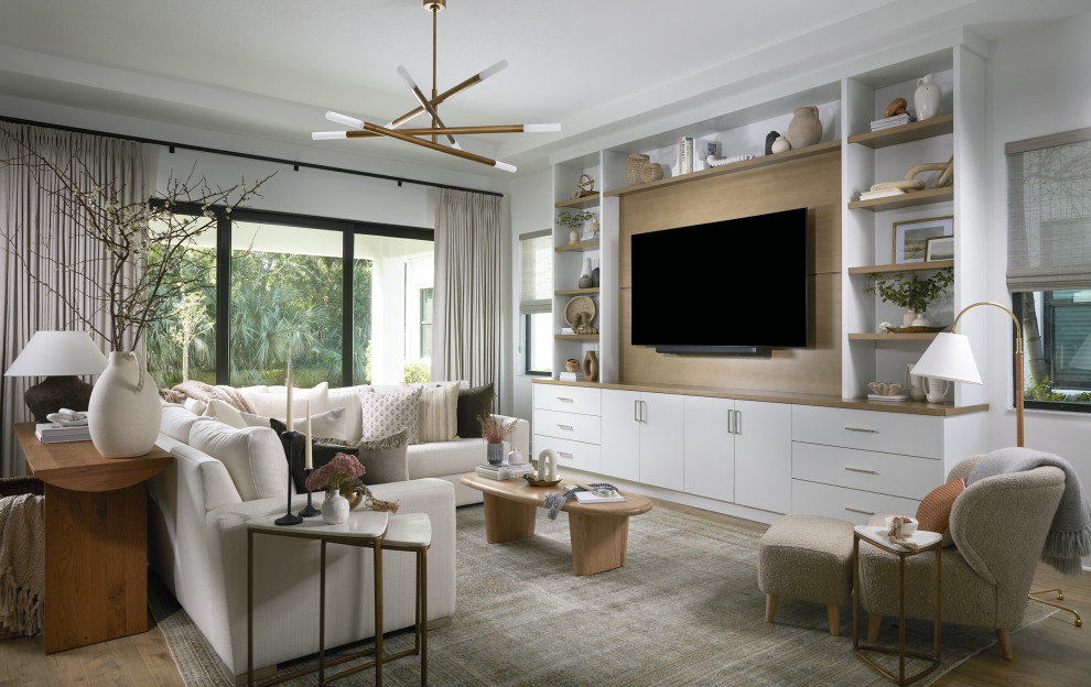 Beach style medium tone wood floor, brown floor and tray ceiling living room photo in New York with white walls and a wall-mounted tv