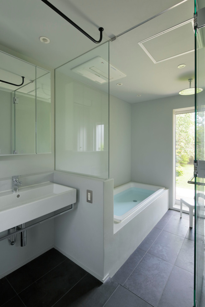 This is an example of a small master bathroom in Other with open cabinets, white cabinets, a drop-in tub, a double shower, white walls, ceramic floors, a wall-mount sink, black floor, a hinged shower door, a single vanity, a floating vanity and timber.