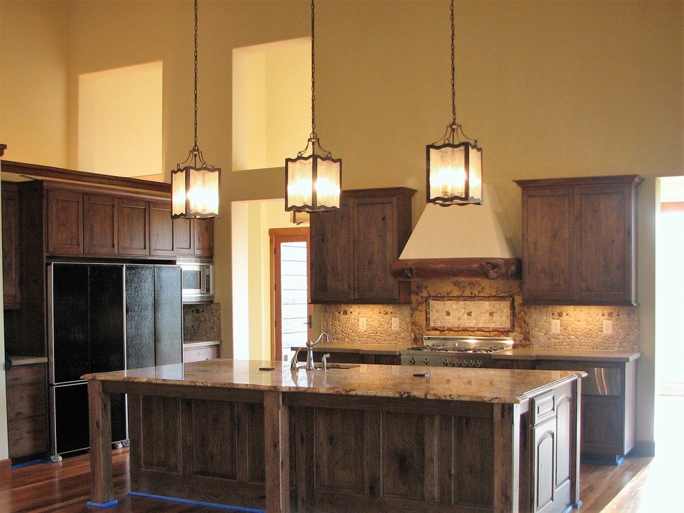 Large mountain style u-shaped medium tone wood floor and brown floor open concept kitchen photo in Seattle with beaded inset cabinets, distressed cabinets, granite countertops, beige backsplash, stone tile backsplash, stainless steel appliances and an island