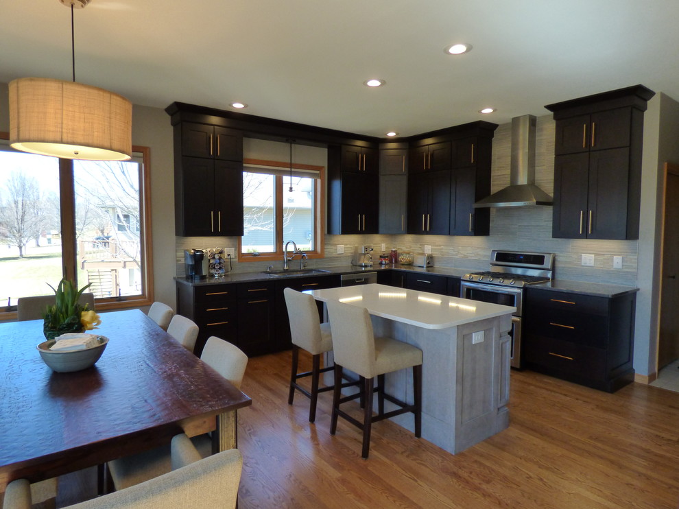 Inspiration for a large transitional l-shaped medium tone wood floor eat-in kitchen remodel in Cedar Rapids with an undermount sink, shaker cabinets, dark wood cabinets, quartz countertops, gray backsplash, porcelain backsplash, stainless steel appliances and an island