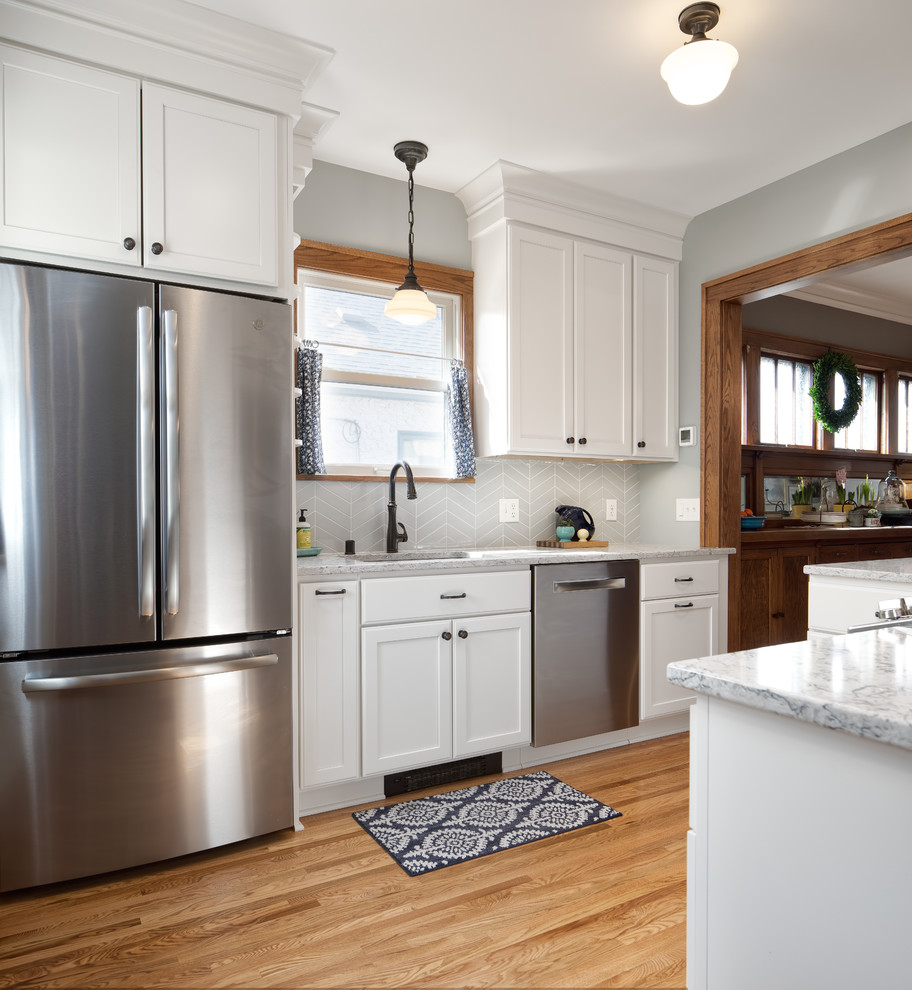 Design ideas for a small transitional u-shaped eat-in kitchen in Minneapolis with an undermount sink, shaker cabinets, white cabinets, quartz benchtops, blue splashback, ceramic splashback, stainless steel appliances, light hardwood floors, a peninsula, brown floor and grey benchtop.