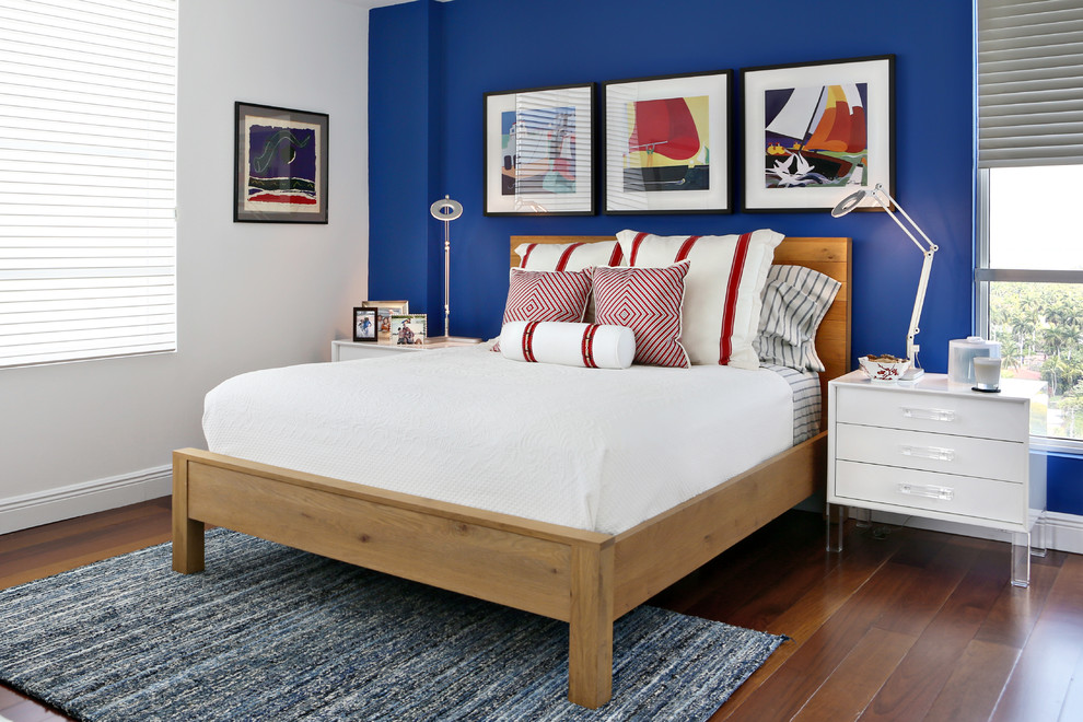 Photo of a mid-sized beach style bedroom in Miami with medium hardwood floors, no fireplace, blue walls and orange floor.